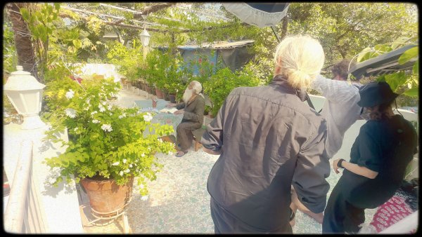 Annie and her team sets up their equipment while Gangadharan sits on his terrace by a table.