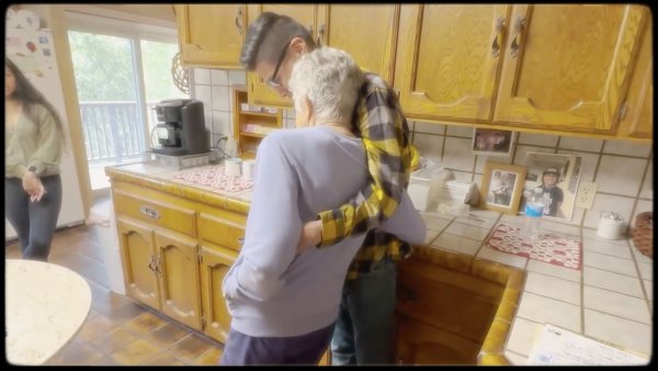 Raul hugging his grandmother in the kitchen.