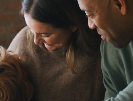 Couple smiling and looking lovingly at a dog