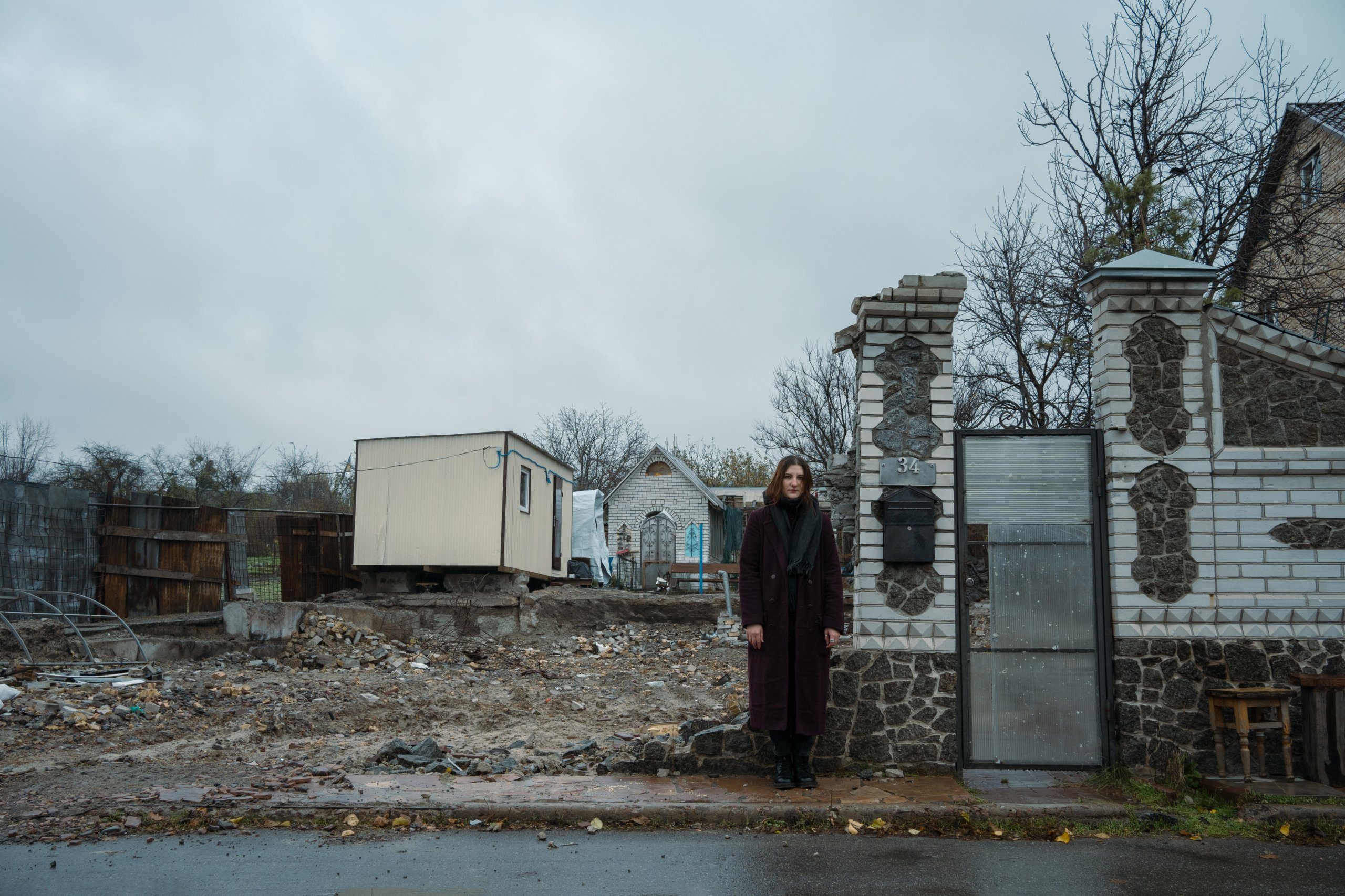 Anna standing next to the gates that once led to her home.