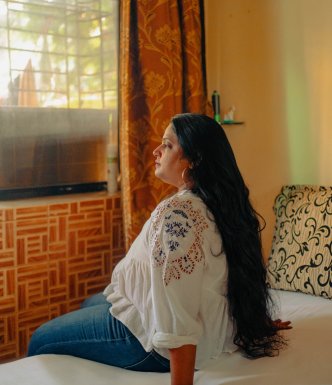 Lady sitting on her bed, looking out of the window