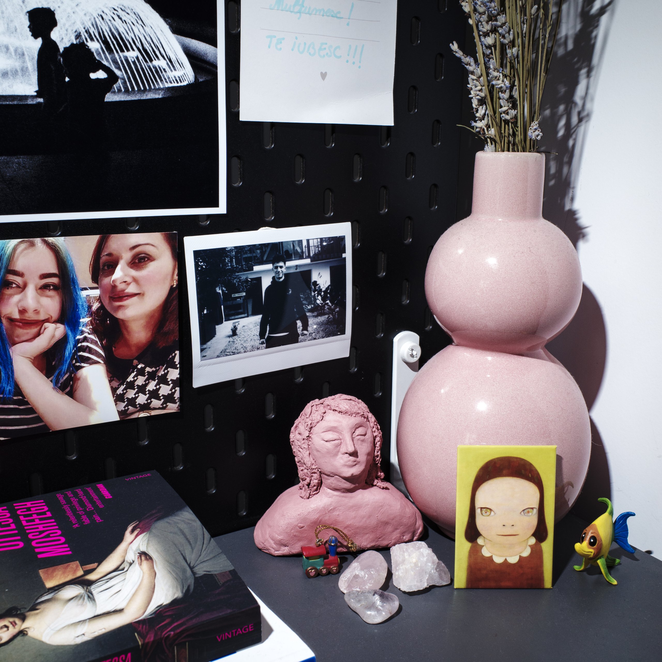 Corner with a pink vase and small, personal decorations.