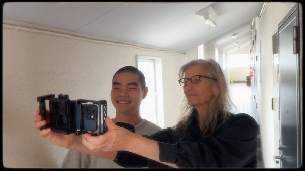 Annie and Sota smiling and looking at photos on a smartphone.