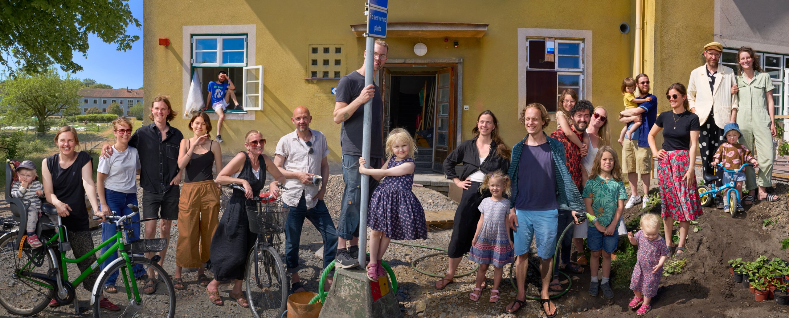 Ludvig and a large group of the people living together standing in front of the house on a sunny summer day.