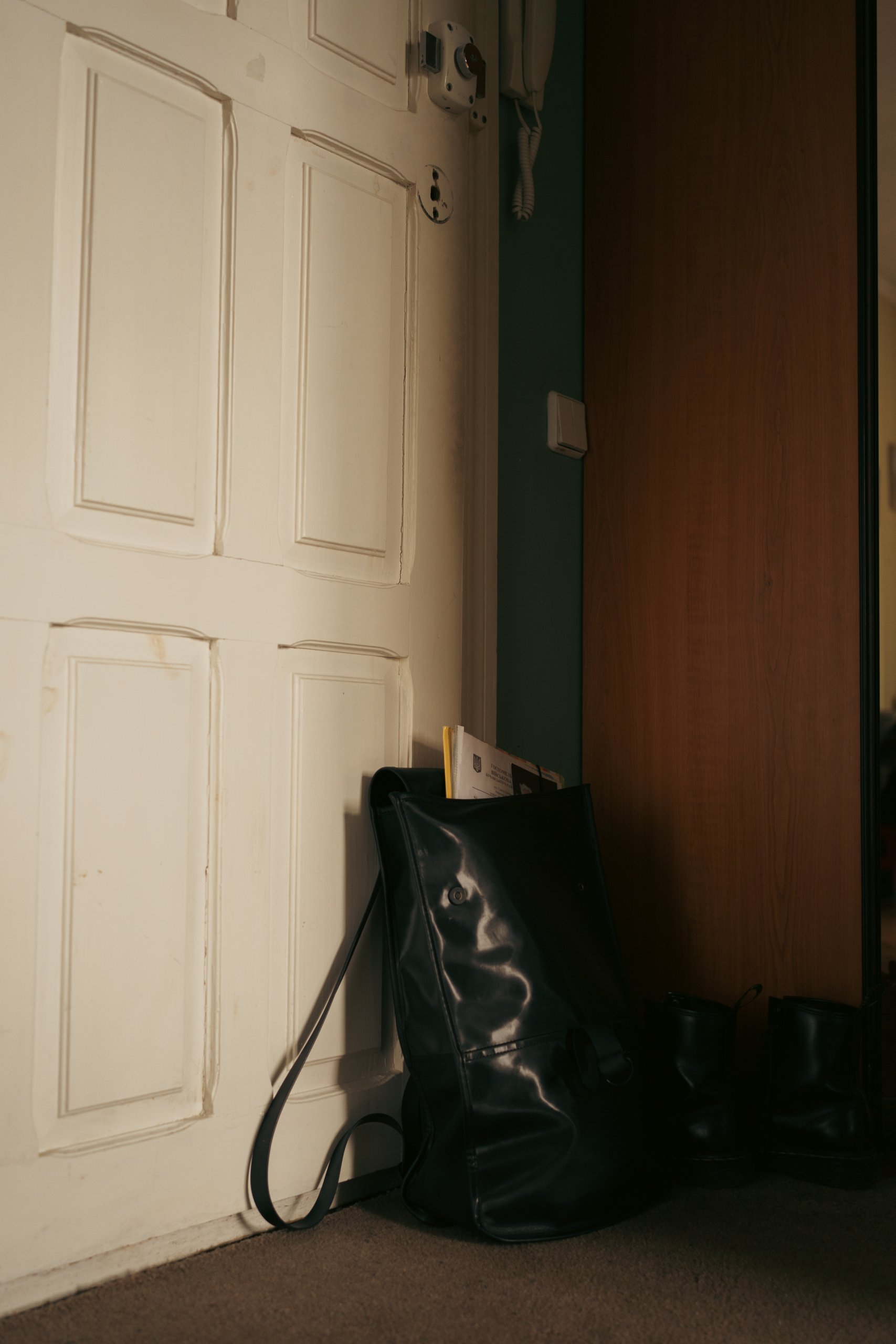 A black bag standing in front of a white door.