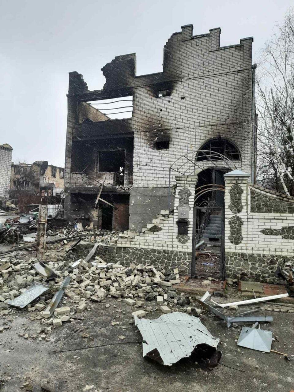 Bombed remains of a house with a gate in front.