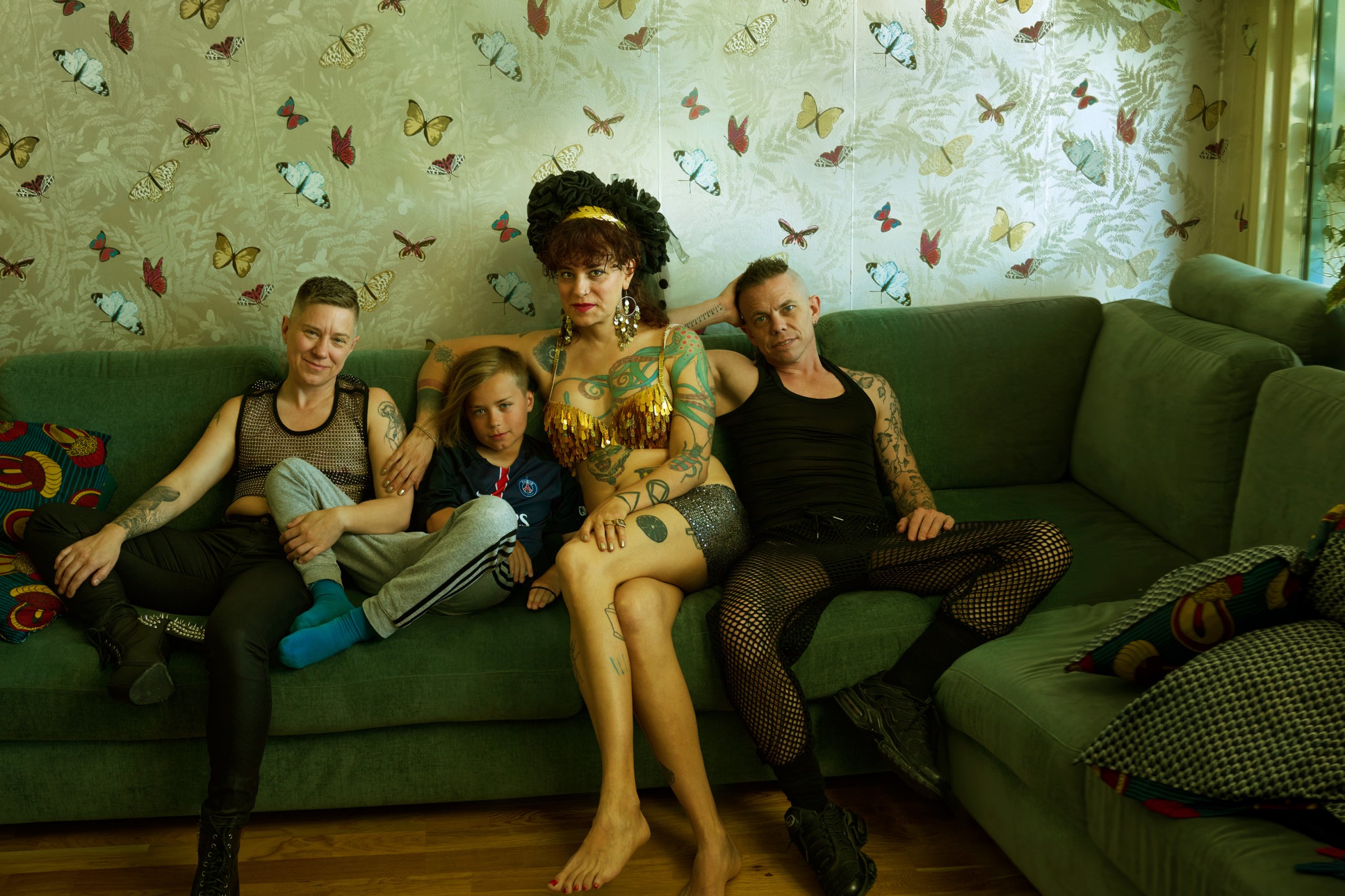 Cal and their family sitting in a green sofa in their living room.