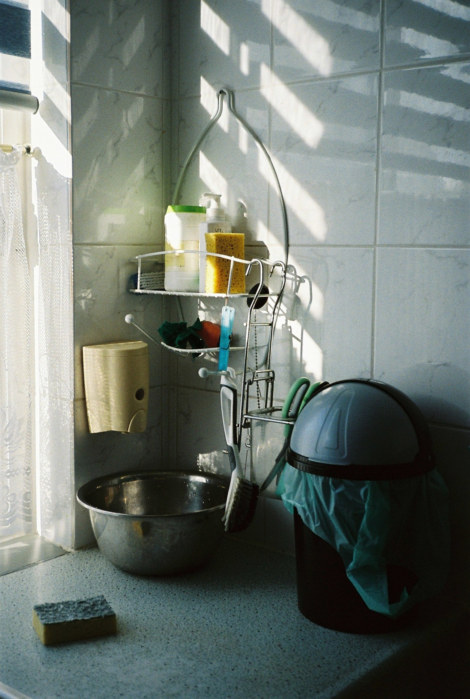 A counter top with kitchen utencils and a trashcan.