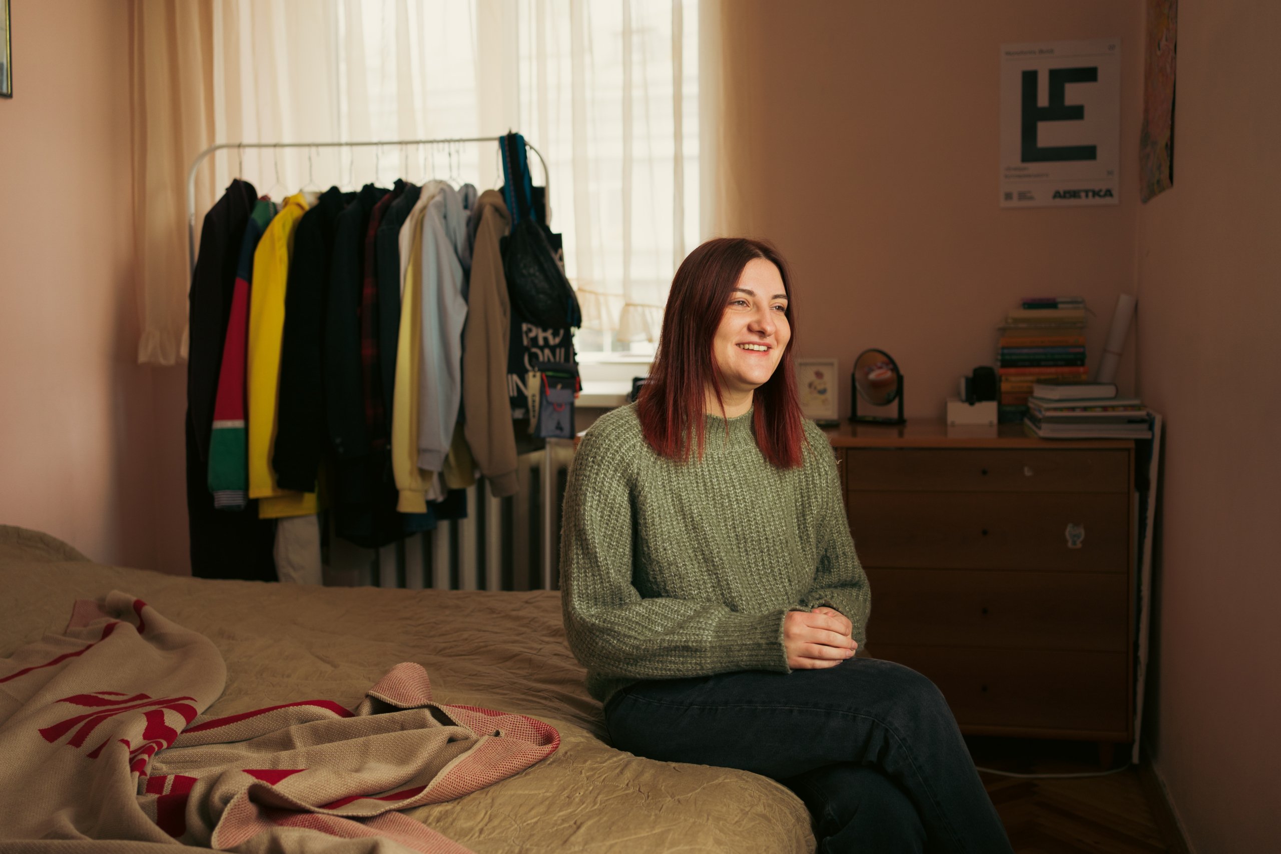 Anna sitting on a bed smiling.