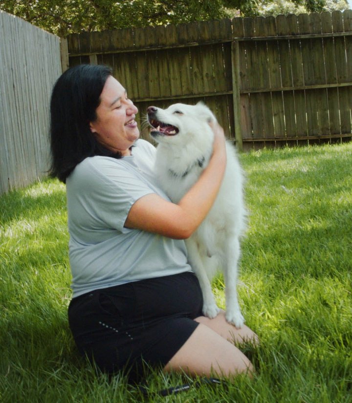 Woman and dog playing in sunny garden