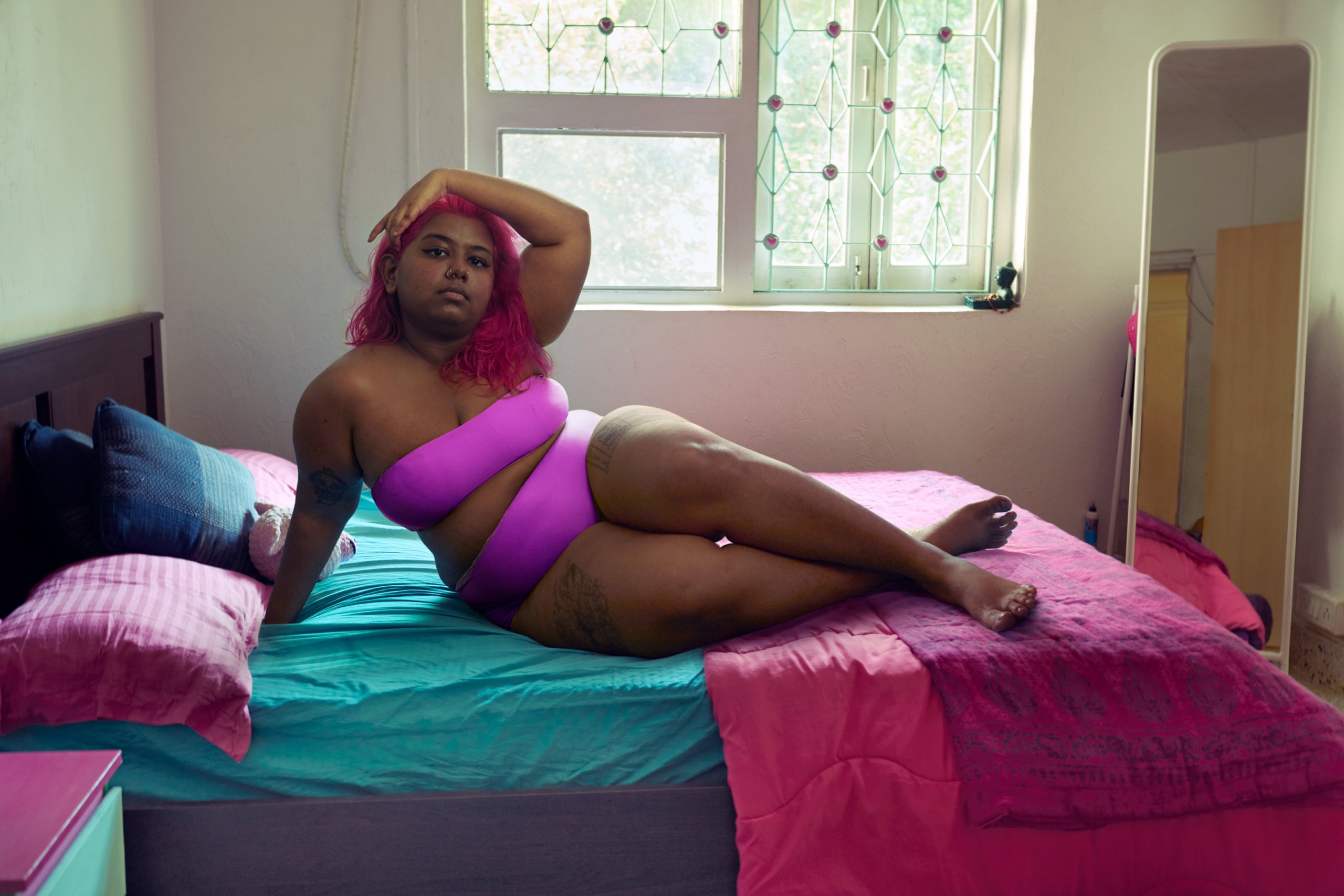 Priyanka sitting on her bed wearing a pink bikini.