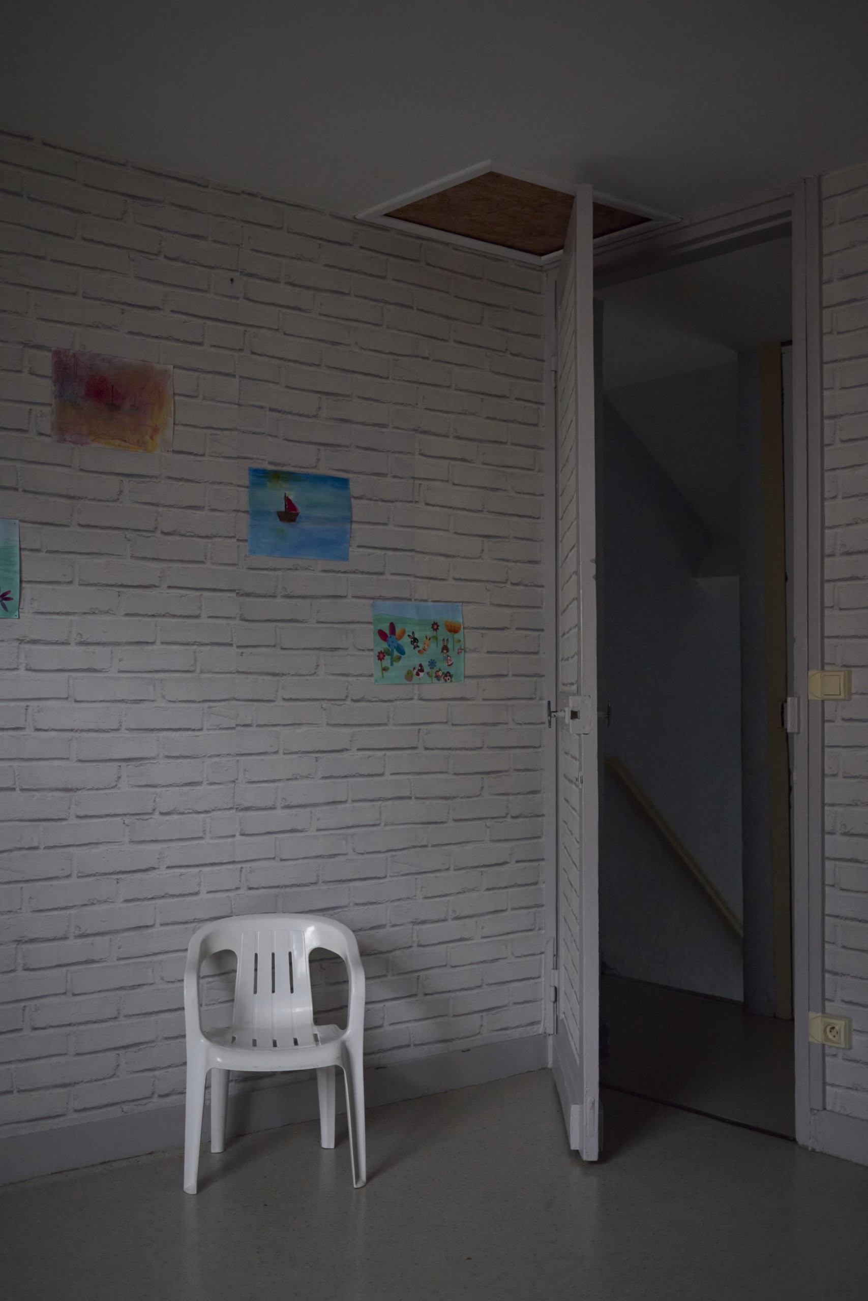 A plastic chair in front of a wall with white brick patterned wallpaper.