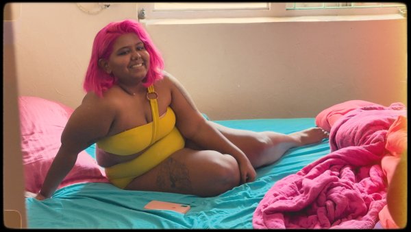 Priyanka sitting on her bed wearing a yellow bikini.
