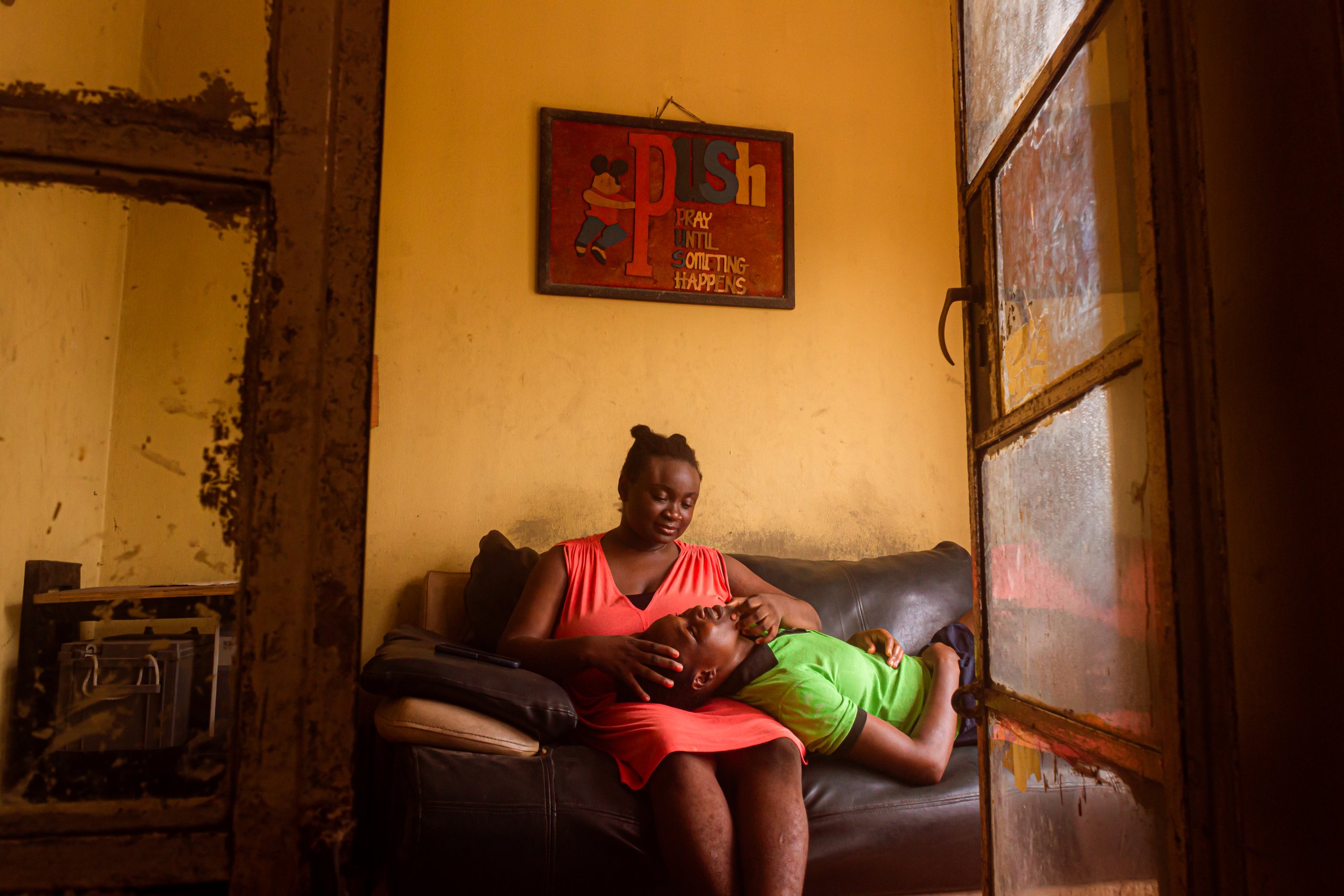 Ife sitting on a sofa with a young man laying in her lap.