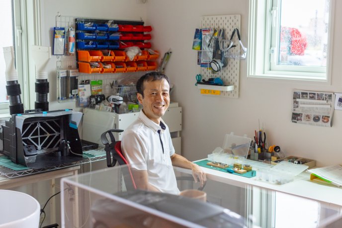 Man smiling in his office, surrounded by his model car making equipment